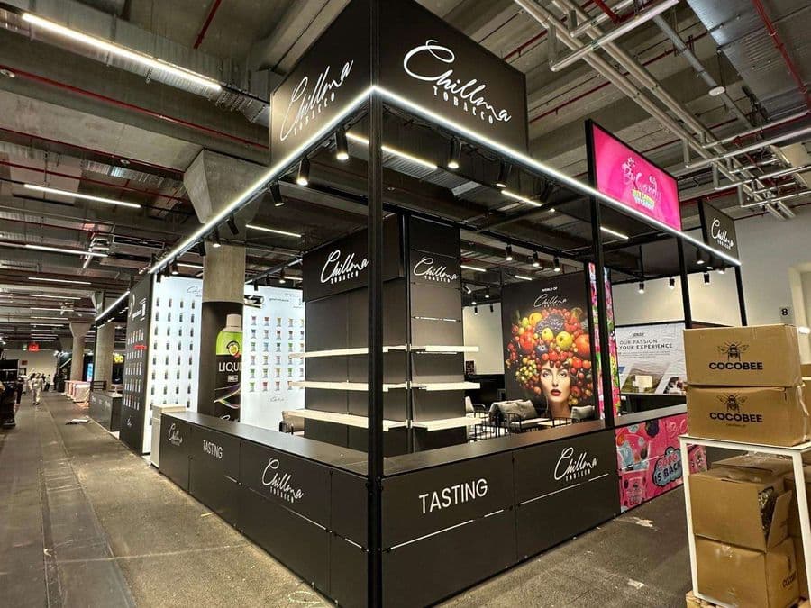 "Chillma Tobacco" markasının şık ve modern fuar standı. Siyah metal iskeletli ve led ışıklandırmalı standın önünde "Tasting" (Tadım) alanı bulunurken, arka duvarda meyvelerle süslenmiş bir kadın portresi yer alıyor.